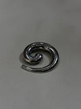 Pin metálico con diseño de espiral en acabado plateado brillante, ideal para personalizar prendas y accesorios.