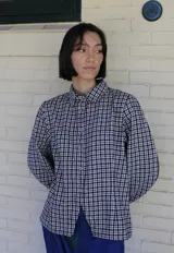 Sobrecamisa de paño con estampado de cuadros vichy en blanco y negro, de corte entallado, cuello clásico, cierre frontal con broches metálicos y mangas abullonadas.