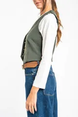 Chaleco verde militar con escote en V, corte al cuerpo y cierre frontal con botones marrones.