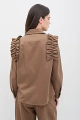 Camisa de gabardina de tencel color negro, con cuello clásico, cierre frontal de botones y volados fruncidos en los hombros.