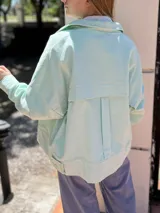 Campera corta de pana color violeta con cuello camisero, cierre frontal con botones dorados, bolsillos de parche en el pecho y corte recto.