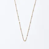 Cadena dorada con eslabones y pequeñas bolitas.