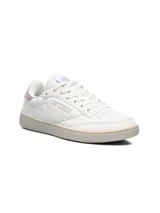 Championes Umbro modelo Rian, de diseño clásico en color blanco con detalles en rosado en el talón y logo lateral. Presentan suela de goma en tono crema y perforaciones en la puntera para mayor ventilación.