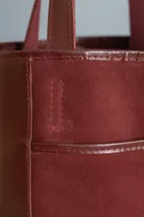 Matera tipo bolso confeccionada en cuero combinado color bordó, con bolsillo frontal exterior y compartimento interno para bombilla.