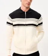 Suéter de punto Marfinno, color blanco y negro con diseño de rayas horizontales bicolor. Cuenta con cuello polo, cierre frontal completo y bolsillos laterales.