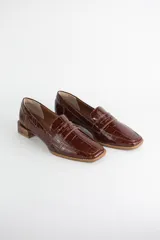 Mocasín clásico de cuero con textura croco acharolada, con taco cuadrado bajo símil madera.
