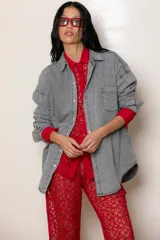 Camisa de jean liviano en tono celeste claro, con corte oversize, cuello clásico, cierre frontal con botones metálicos, bolsillo en el pecho y detalle de bordado en el puño.