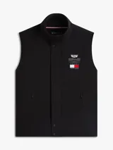 Chaleco negro con cuello chimenea, cierre de cremallera oculto con botones a presión y dos bolsillos laterales ribeteados. Presenta logos bordados en el pecho de Tommy Hilfiger y Cadillac Formula 1 Team.