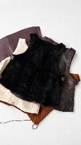 Chaleco negro de corte oversize con costuras a la vista en color contraste, cuello redondo y hebillas ajustables en los laterales.