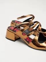 Sandalias de cuero con acabado de charol metalizado en color dorado, con tiras cruzadas en el empeine, taco cuadrado de 4,5 cm y correa ajustable en el tobillo.