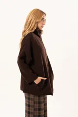 Tapado tipo poncho de color chocolate, confeccionado en tejido de paño, con cierre frontal completo metálico, cuello alto y bolsillos laterales.