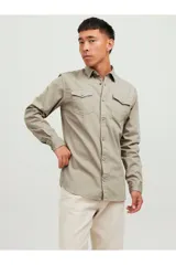 Camisa de denim color beige, con cuello clásico, cierre con botones y dos bolsillos frontales con solapa abotonada. Corte slim.