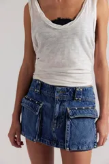 Minifalda de denim azul de tiro bajo, con bolsillos cargo frontales con tapa, detalles de tachas metálicas y costuras pespunteadas.