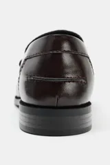 Mocasín plano de mujer con acabado acharolado color bordó. Presenta un diseño con fruncidos en el empeine y una hebilla metálica dorada decorativa. Cuenta con punta redonda y suela plana de 2,5 cm.