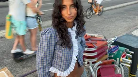 Camisa crop de manga larga con estampado de cuadros en tonos azules y amarillos. Presenta un diseño con volados de encaje blanco en la parte frontal y en el ruedo, con cierre de botones.