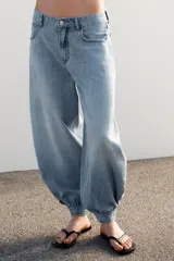 Jeans negro de tiro medio con corte balloon fit, diseño de cinco bolsillos y bajo acabado en puño con abertura y botón.