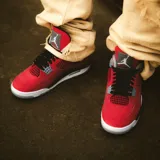 Championes Air Jordan 4 Retro en color rojo con detalles en negro, gris y blanco, confeccionados con paneles de malla y refuerzos plásticos característicos del modelo.