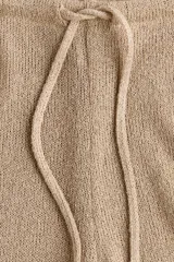 Pantalón de punto color marrón, de tiro medio con cintura elástica, cordón ajustable y corte ancho.