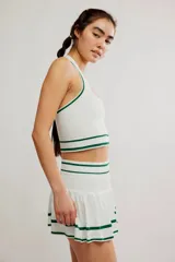Conjunto deportivo compuesto por un top halter y una pollera pantalón de color blanco con líneas horizontales verdes.
