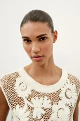 Top de crochet color crudo, sin mangas, con cuello redondo y detalle de aplicaciones de flores en relieve.