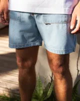 Bermuda de jean celeste con dos bolsillos frontales tipo parche, costuras a contratono y botones de cobre.