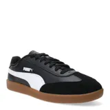 Championes urbanos Puma modelo 9T, con diseño inspirado en el fútbol sala. Presentan una combinación de cuero sintético negro en los laterales y gamuza negra en la puntera, con la icónica franja lateral de Puma en color blanco y suela de goma color caramelo.