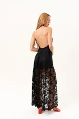 Vestido largo de encaje negro con cuello halter, compuesto por un minivestido base y una sobrefalda transparente de encaje con diseño floral.