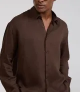 Camisa de corte relajado confeccionada en cambraia de lino puro. Presenta cuello inglés, cierre frontal con botones y mangas largas.