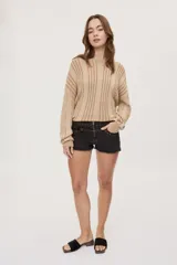 Short de tiro bajo de denim color marrón, con terminación desflecada en el ruedo, bolsillos delanteros, cierre frontal y detalles de tachas en la cintura.