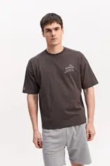 Remera boxy de algodón color beige, de silueta amplia y corta, con mangas cortas y pequeño estampado en el pecho.