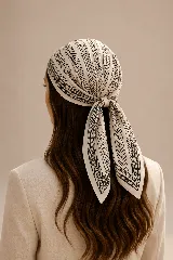 Pañuelo cuadrado de seda con estampado geométrico en tonos crema y negro, diseñado para anudarse en la cabeza.