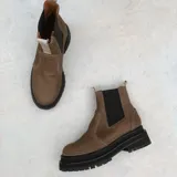 Botas estilo Chelsea de cuero color marrón, con paneles elásticos laterales negros, presillas traseras y suela chunky de goma negra con plataforma dentada.