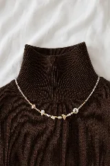 Collar de cuentas pequeñas transparentes y perlas, intercaladas con piezas irregulares de piedra y detalles metálicos dorados.