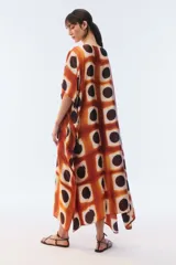Kaftan maxi amplio de color amarillo, con escote redondo, mangas cortas y ruedo irregular. Presenta un diseño estampado a cuadros con efecto teñido.