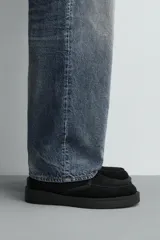 Bota de caña media con cordones, confeccionada en piel con acabado en serraje. Presenta horma redonda, forro interior de pelo sintético y suela de goma con volumen.