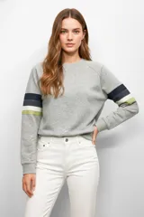 Buzo de cuello redondo y manga larga con diseño de franjas horizontales en tonos azul marino, blanco y verde en las mangas. Presenta puños y ruedo acanalados.