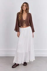 Blusa crop top marrón con escote en V pronunciado, mangas largas acampanadas y cierre de lazo delantero. Tiene detalles de apliques metalizados en el borde del escote y un diseño fruncido en la parte inferior.