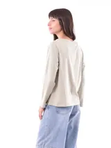 Remera de manga larga color azul, con cuello redondo y un estampado central de flores en tonos pastel sobre un recuadro gris claro.