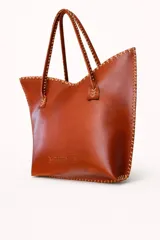 Cartera de cuero mediana con manijas largas, diseño con borde superior en corte en V y terminación artesanal con costuras contrastantes.