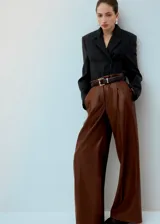 Pantalón de corte wide leg, confeccionado en material sintético efecto cuero color marrón, con pinzas en la cintura y bolsillos laterales.