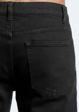 Pantalón de sarga de corte ajustado, color verde oscuro, con diseño clásico de cinco bolsillos y cierre frontal con botón y cremallera.