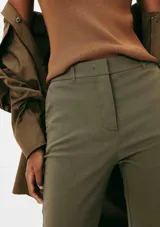 Pantalón de sastre negro de corte ajustado y tobillero, de tiro alto con cierre frontal.