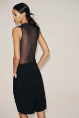 Body negro de tul con cuello alto y sisas amplias. Diseño drapeado en el frente y cierre inferior con broches a presión.