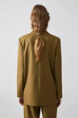 Blazer sastrero color verde oliva, de solapa amplia y fit recto. Cuenta con acceso por botón central, bolsillos delanteros, hombreras y forro completo.