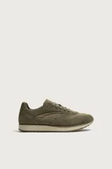 Zapatilla deportiva de estilo casual, confeccionada en una combinación de piezas de cuero con acabado serraje. Presenta horma redonda, cierre con cordones y suela dentada en contraste.