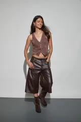 Bermuda de cuerina color marrón oscuro, de corte ancho y largo por debajo de las rodillas, con diseño de tiro medio y costuras horizontales en las piernas.