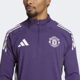 Buzo de entrenamiento Adidas Tiro 25 del Manchester United, color violeta con detalles en blanco. Posee cuello alto con cierre parcial, mangas largas con aberturas para los pulgares y tecnología AEROREADY para el control de la humedad. Presenta el escudo del club y el logo de la marca estampados en el pecho.
