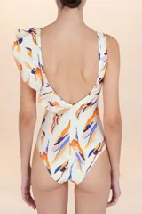 Traje de baño entero blanco con estampado abstracto en tonos naranja, azul y rosado. Presenta escote en V cruzado y un volado asimétrico que cae sobre un hombro.
