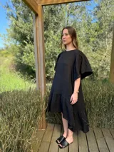 Vestido negro de lino, corte holgado, largo asimétrico, mangas cortas amplias y cuello redondo.