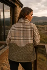 Campera de diseño combinado con cuello alto y cierre frontal. La parte superior presenta un estampado a cuadros en tonos beige y marrón, mientras que la parte inferior es de color verde oliva con un diseño acolchado en forma de rombos.